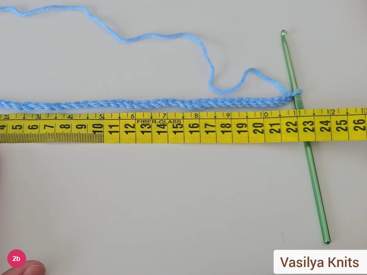 Long blue chain lying along a yellow tape measure with its end at about 22 cm and the hook at the end