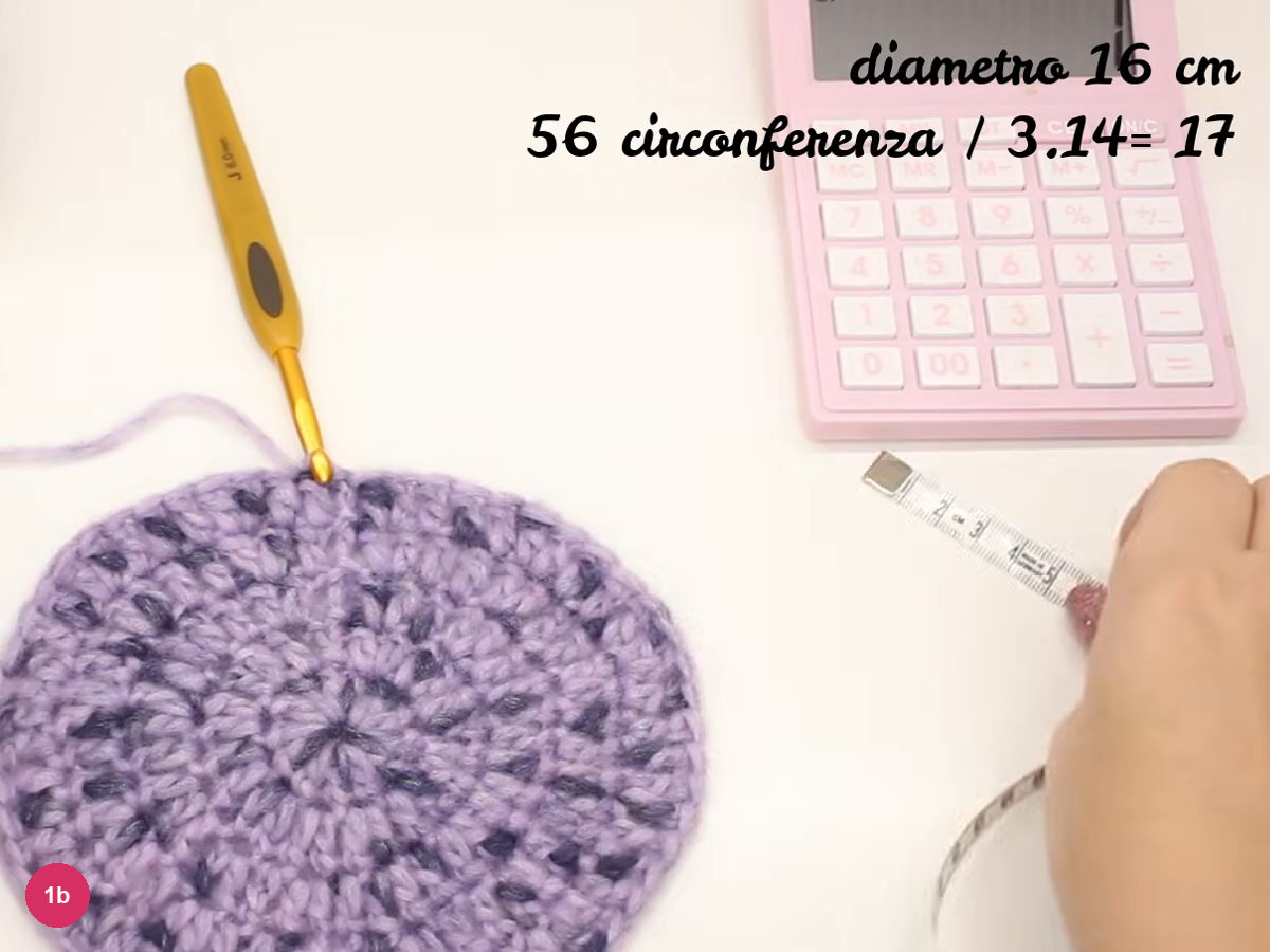 Flat lilac crochet disc beside a pink calculator and tape measure, with on-screen text 56 circumference divided by 3.14 equals 17 and diameter 16 cm