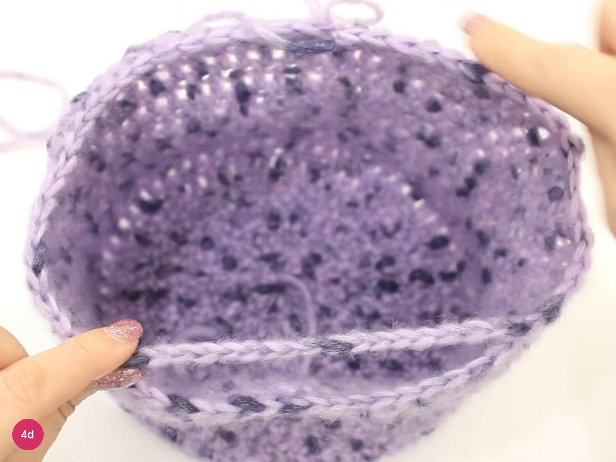 Looking down into the lilac cap with one chain strand stretched across its open rim, held at the left end by a fingertip