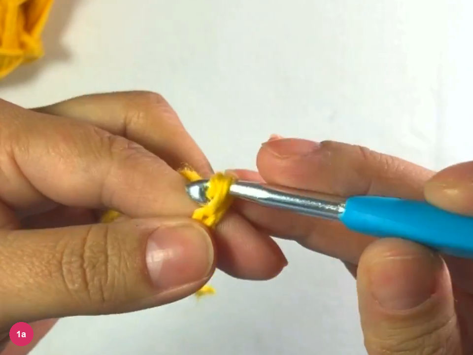 Hook holding a short yellow chain, with the working yarn hanging below the left hand