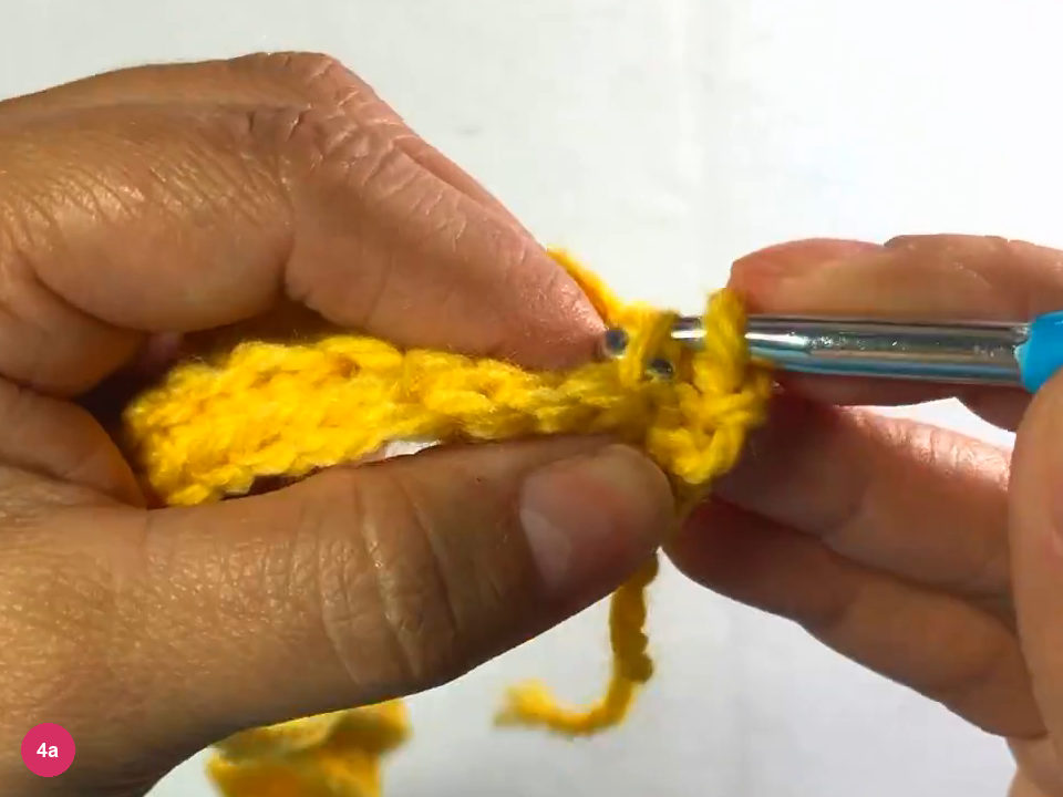 Hook starting a new row on a short ribbed strip held between both hands