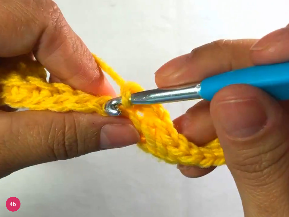 Hook working along a row of the growing ribbed strip, with a loose end of fabric hanging below