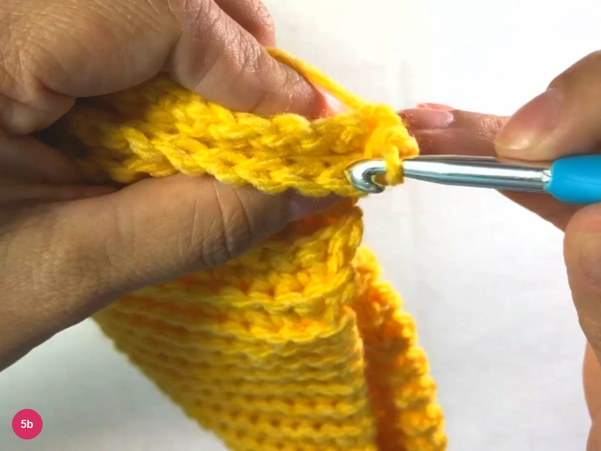 Hook joining the two ribbed edges with a slip stitch while the fingers hold the folded fabric