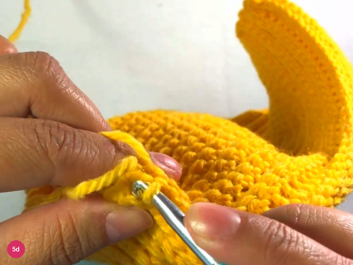 Hook slip stitching at the end of the seam, fingers holding the edge, with the open tube curving behind