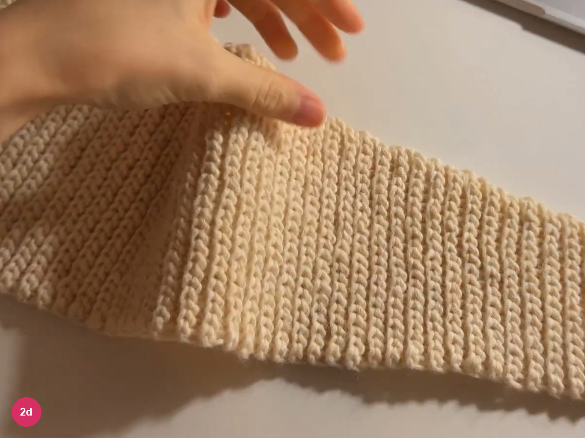 Long cream ribbed tie spread across the tabletop beneath the hand