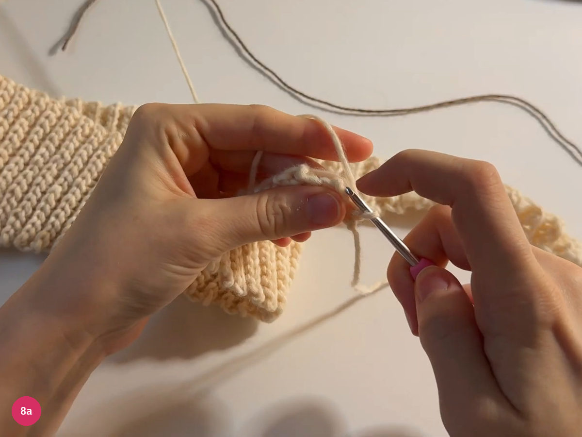 Cream slip-stitch edging held on the hook along the ribbed perimeter