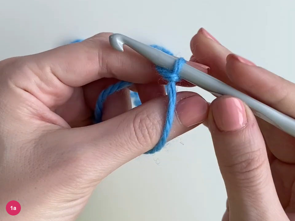 Blue starting loop around a grey crochet hook between the hands