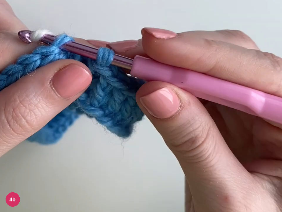 White yarn being drawn through the blue round join on a purple hook