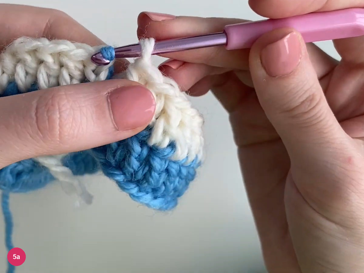 Purple hook at the white round join beside the waiting blue yarn