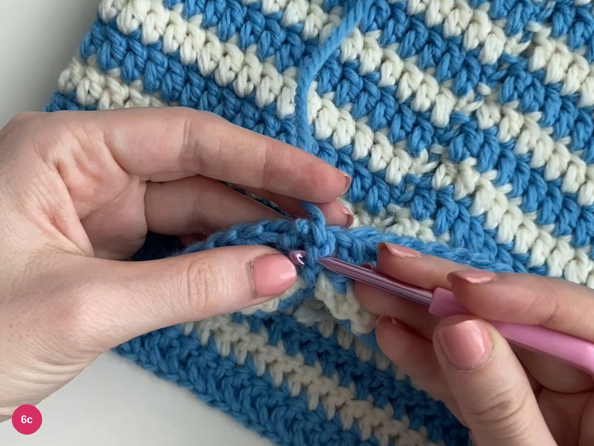 Purple hook carrying the blue tail through blue stitch bases on the striped fabric