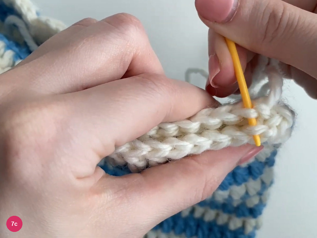 Yellow needle passing through white loops along the paired upper edges
