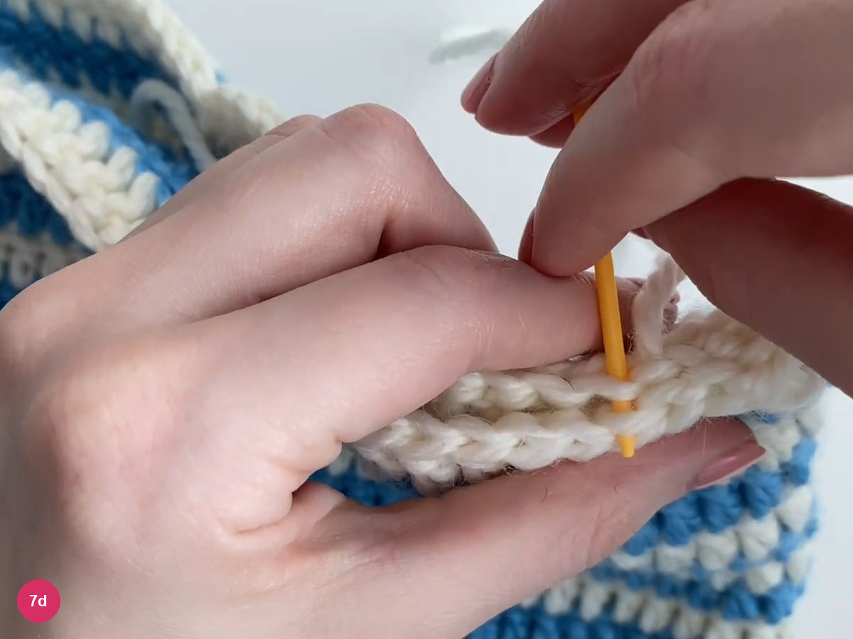 White seaming yarn drawn through the nearly closed top edge