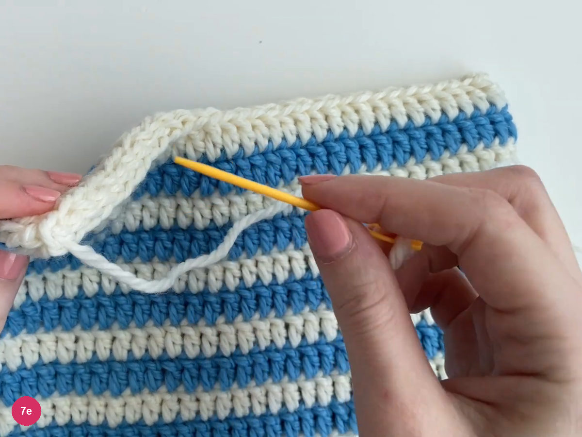 Yellow needle and white tail being taken inside at the end of the top seam