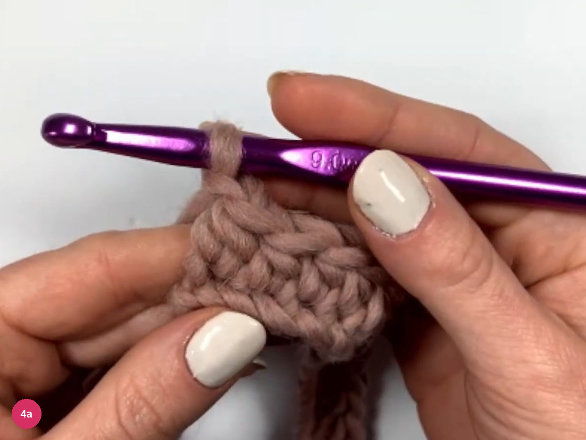 A small piece of rose crochet held in both hands with the hook resting on the top edge, ready for the turning chain