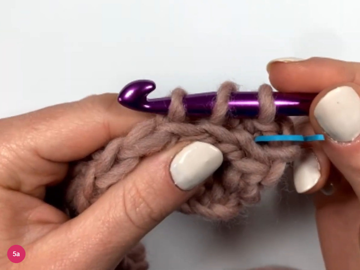 Hook with three loops above row 3 and a blue marker lying across the first stitch