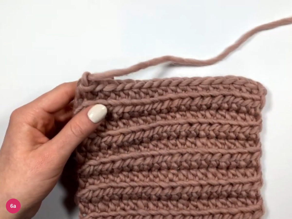 Finished ribbed panel on a white table with a long yarn tail leaving the top left corner
