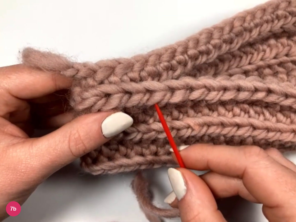 Panel folded so the two side edges meet, with a red needle entering the first stitches of the seam