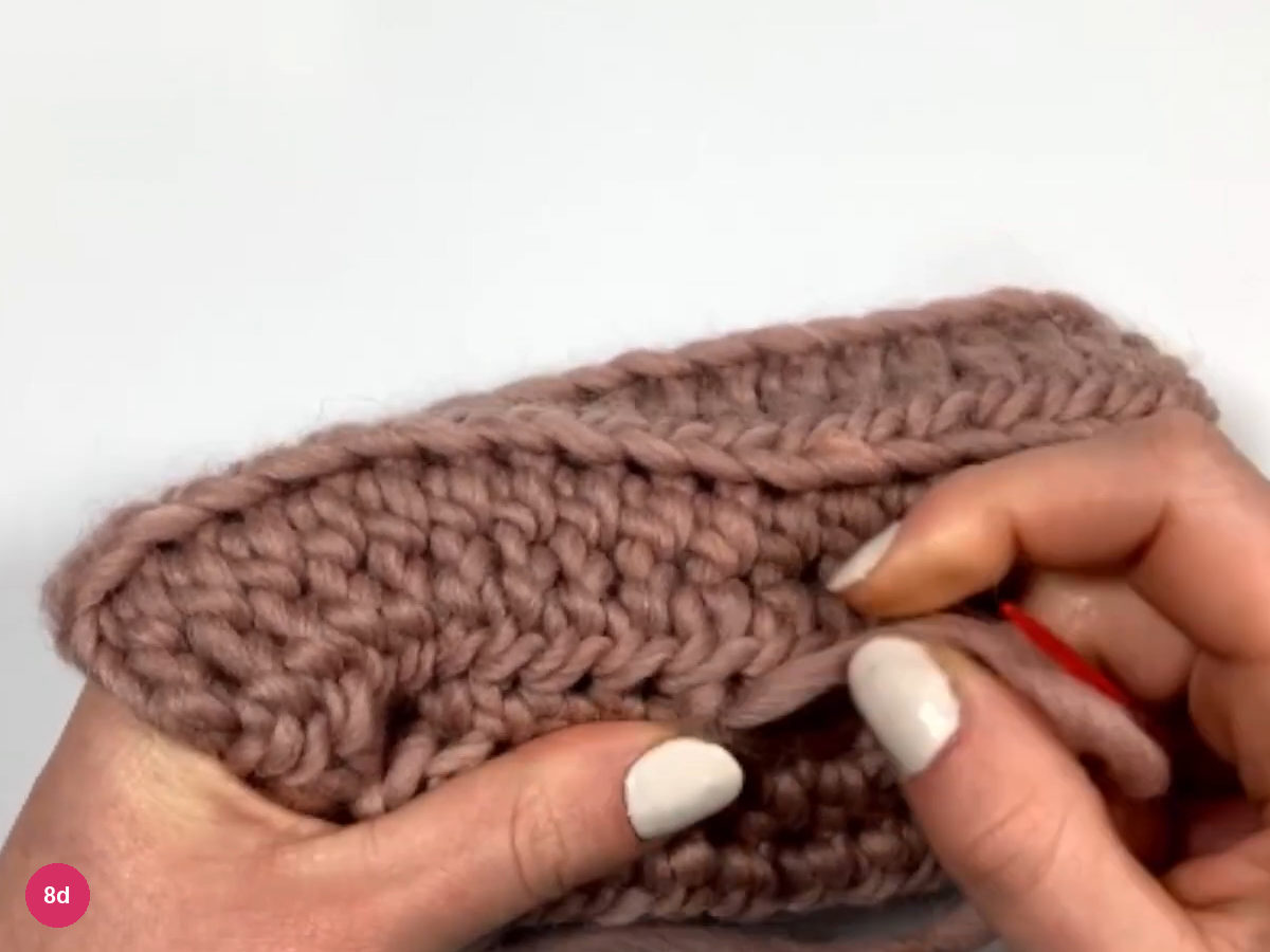 Inside of the sleeve held in both hands with the needle and yarn near the finished seam