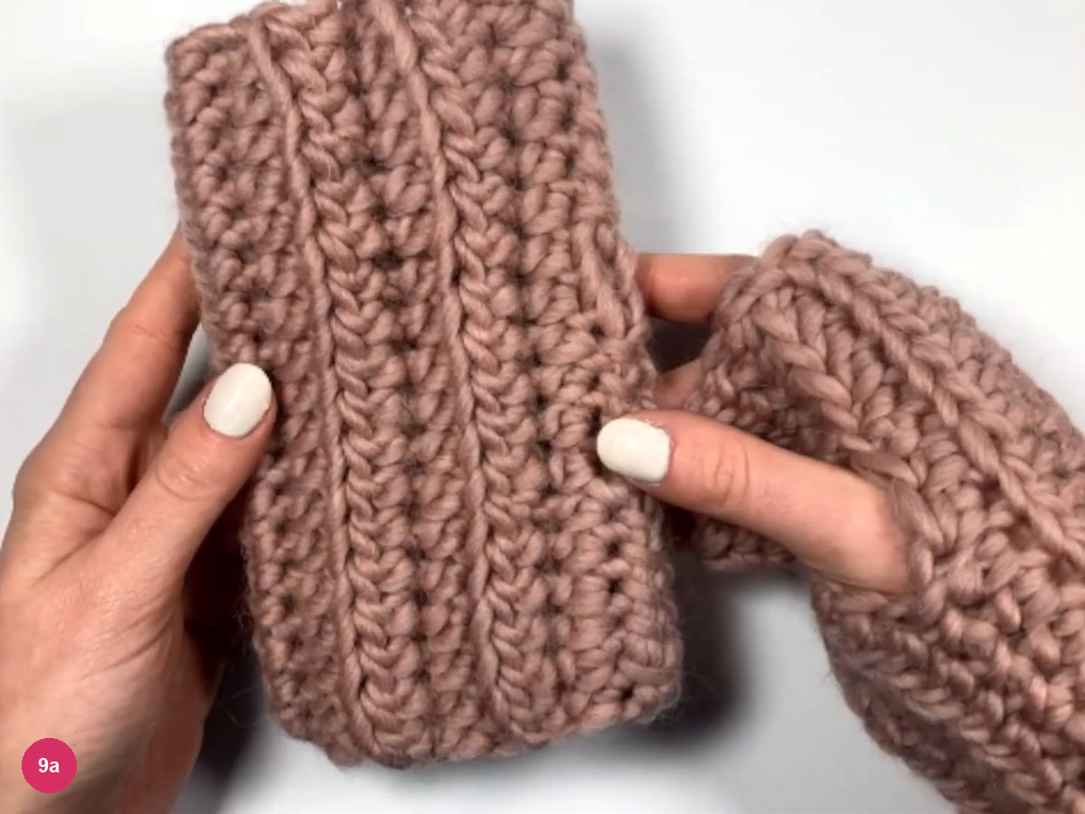 One finished ribbed glove held upright beside a second glove showing its thumb opening
