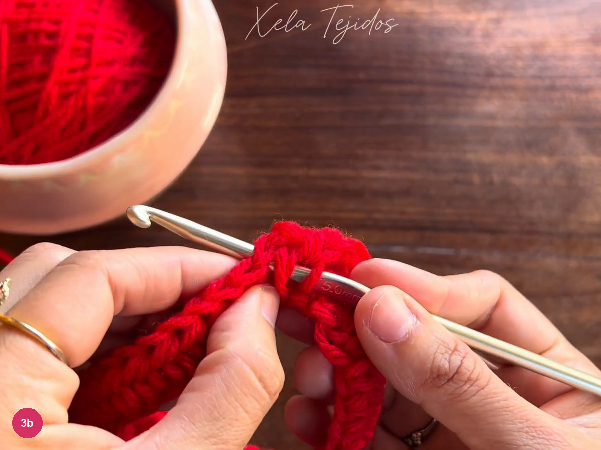 Metal hook inserted under both red loops of a body stitch