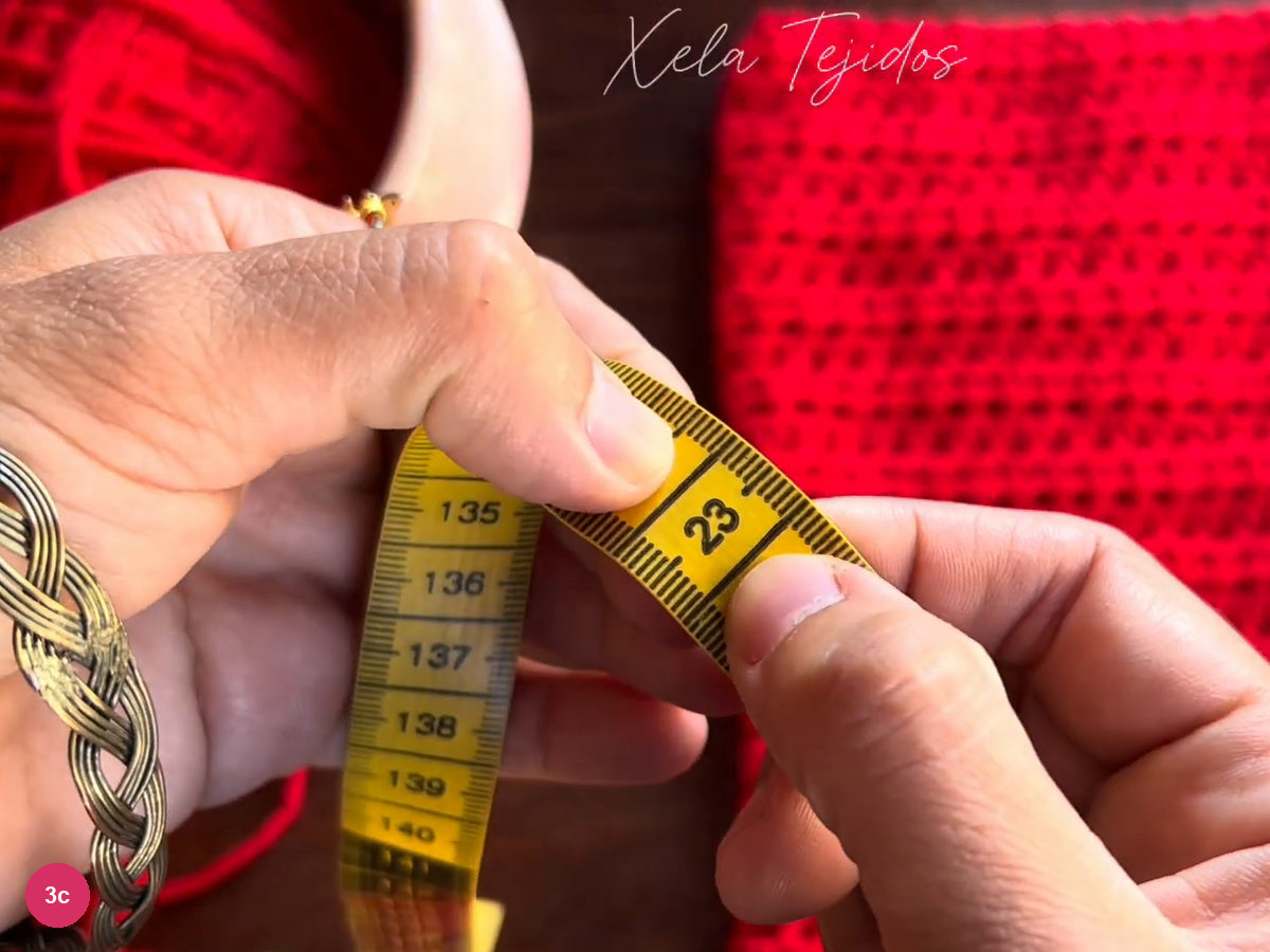 The 23 cm mark on a yellow tape held in front of the red crochet tube