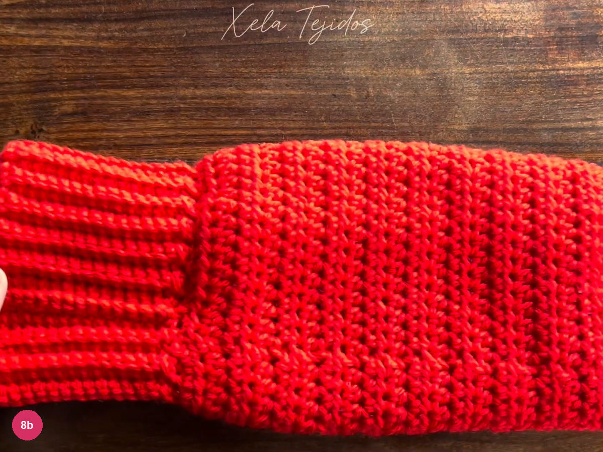 Completed red body and ribbed cuff held up for a finished-join check