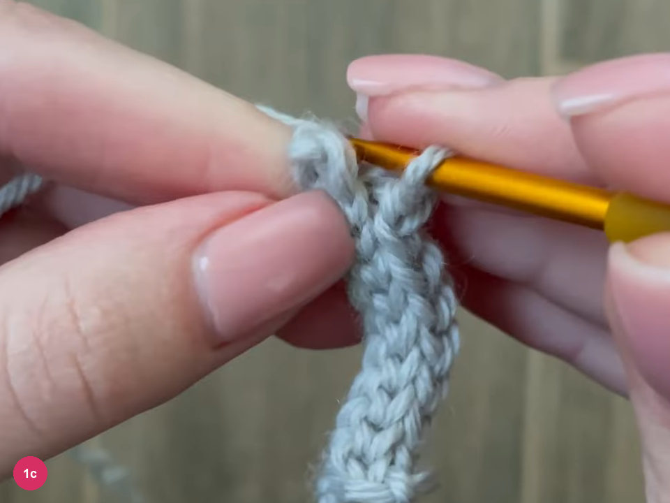 Two-row light grey ribbed strip with the hook at its top held between fingers