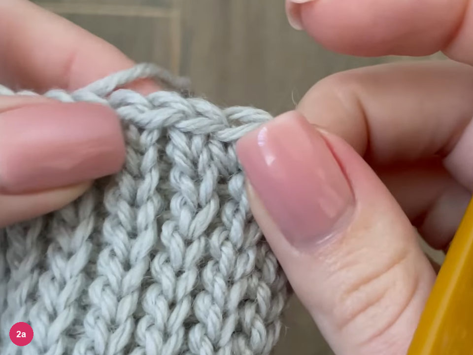 Top edge of the ribbed cuff showing a row of single crochet stitches worked along the ridges