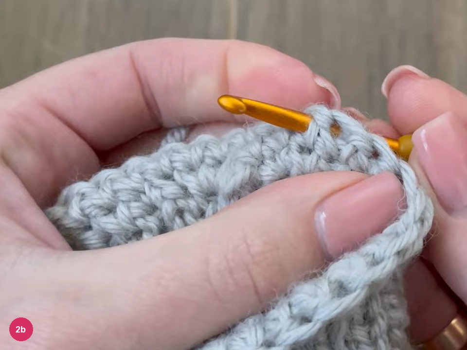 Hook inserted into the top edge of the ribbed cuff while working single crochet
