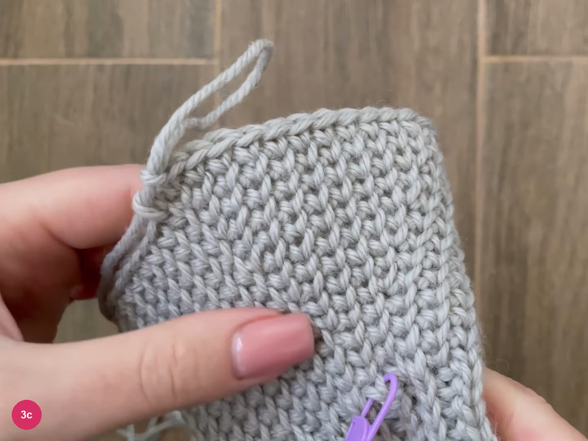Widened single crochet hand section with a purple marker at its bottom edge and a yarn tail at the top