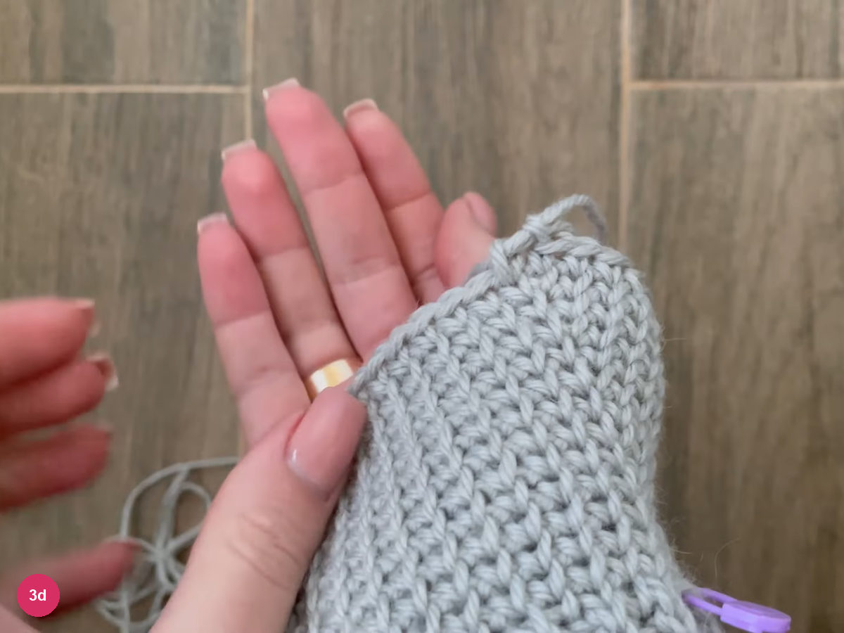 Widened single crochet gusset section held next to an open palm with a marker at its edge