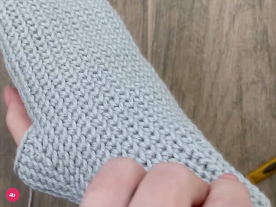 Tube of single crochet laid over a hand with the thumb gap at its side