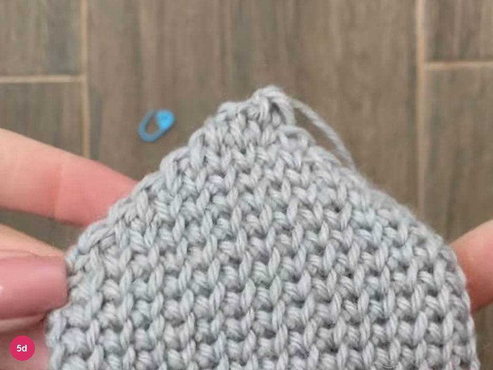 Narrow closed top of the mitten with the cut yarn tail