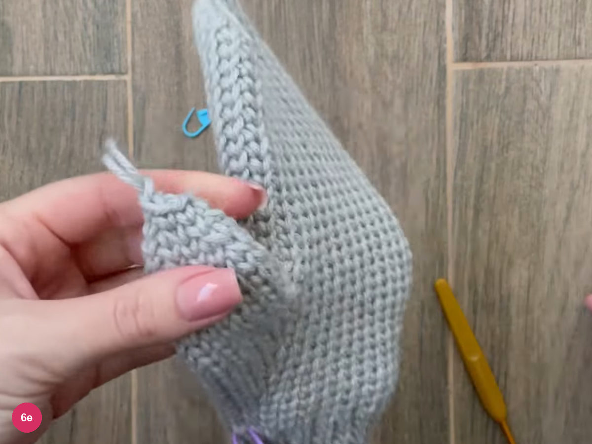 Thumb tip drawn closed with the yarn tail, held beside the mitten body