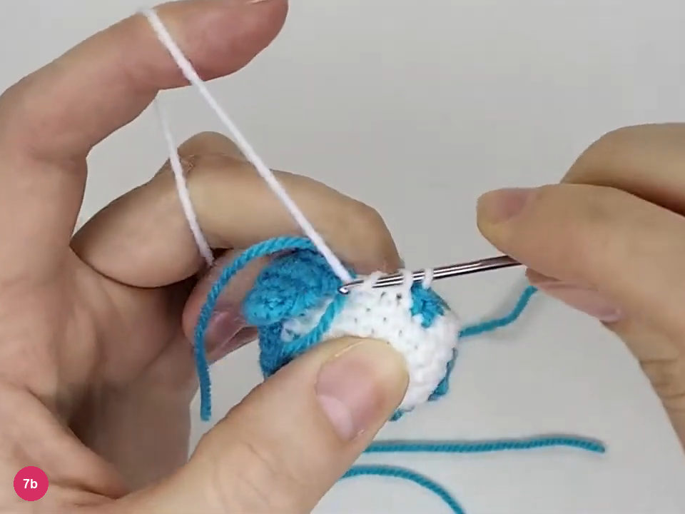White loops on the hook while working the second face group beside the turquoise divider