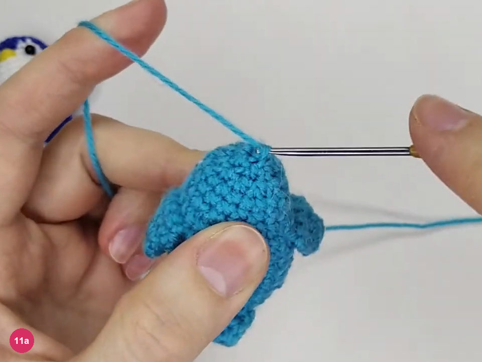 Hook drawing turquoise yarn through the final crown loops