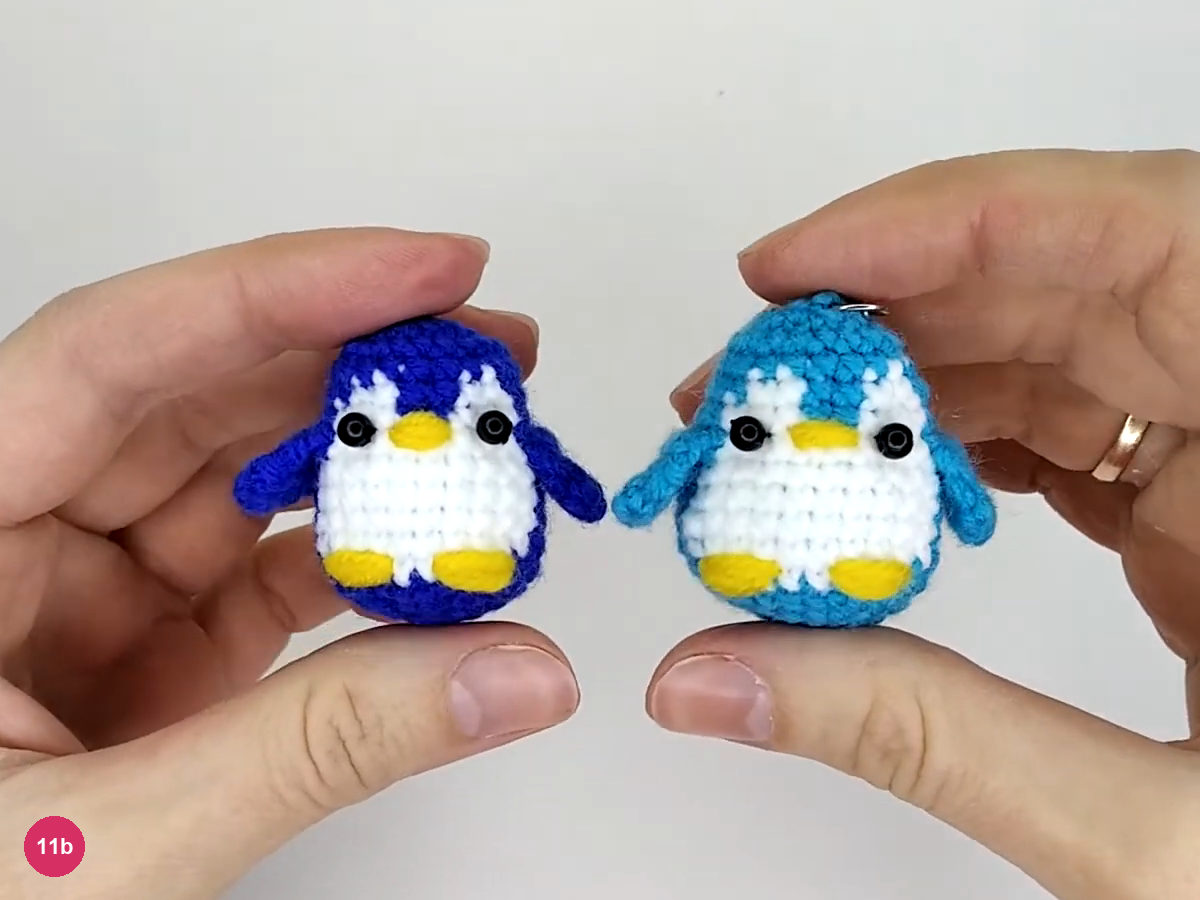 Turquoise and navy 3.5 cm mini penguins held between fingertips, with the turquoise key-ring attachment visible
