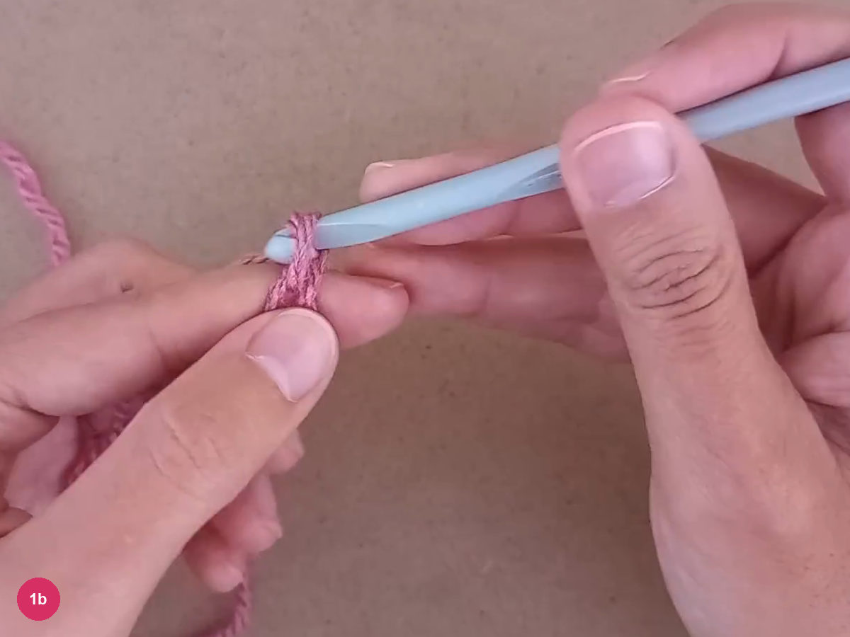 Foundation chain held between the hands with a pale crochet hook in the active loop