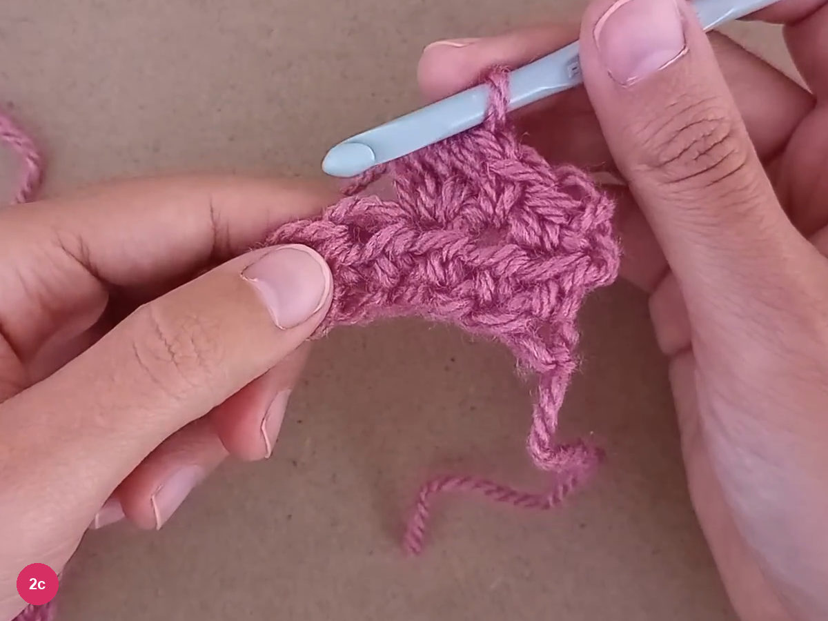 Closed bobble beside the hook with the next stitch exposed on the rose strip