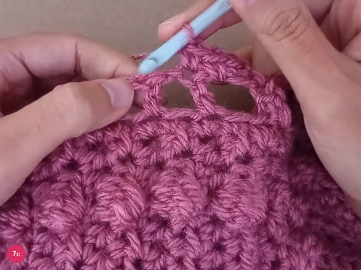 Small single-crochet stitches being worked over the open neck-border spaces
