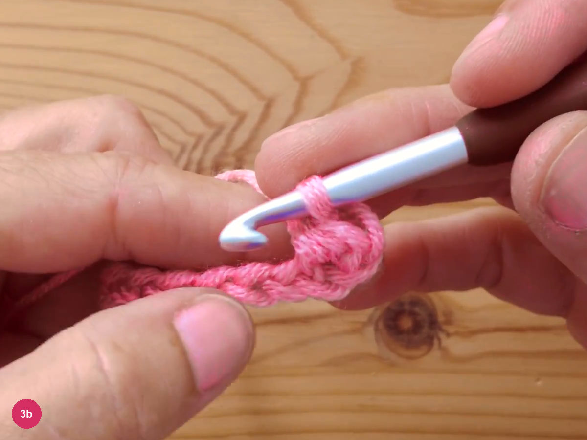 The hook tip just after pulling through, with the finished first half double crochet stitch sitting on the base chain