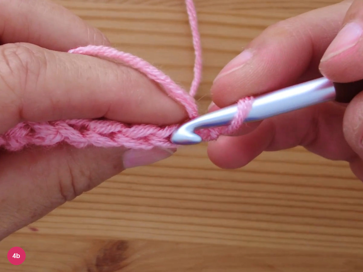 The hook slipped under the back loop of a stitch along the top of the previous row, yarn held across the left finger