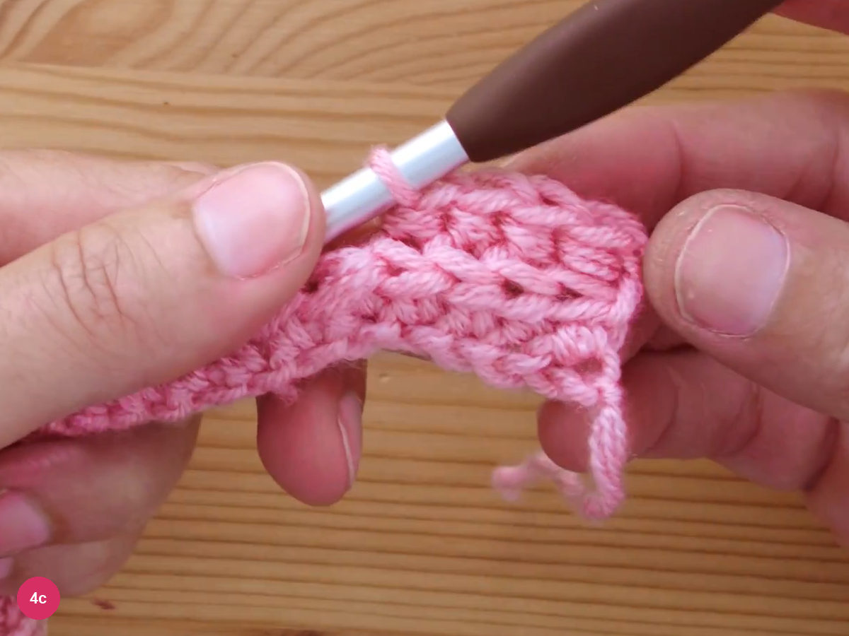 A small piece of ribbed fabric with raised horizontal ridges forming, the hook resting above the last stitch