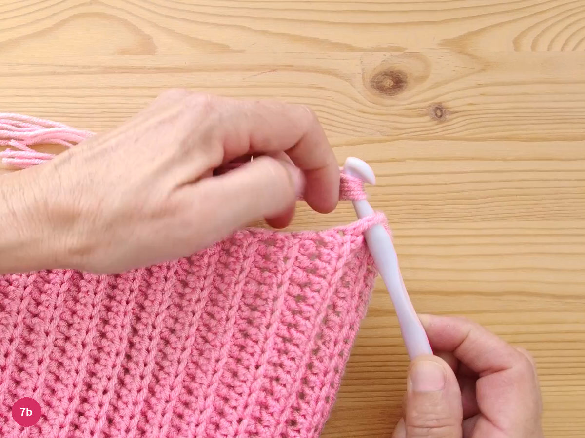 A bundle of folded pink strands caught on the hook at the edge of the ribbed fabric