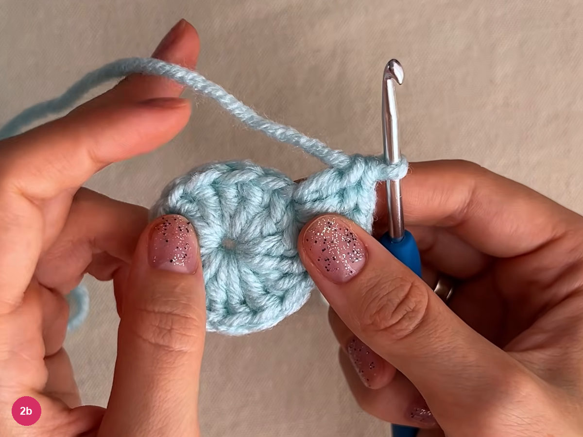 Flat mint round with stitches radiating from a small centre and the working loop on the hook at its upper right