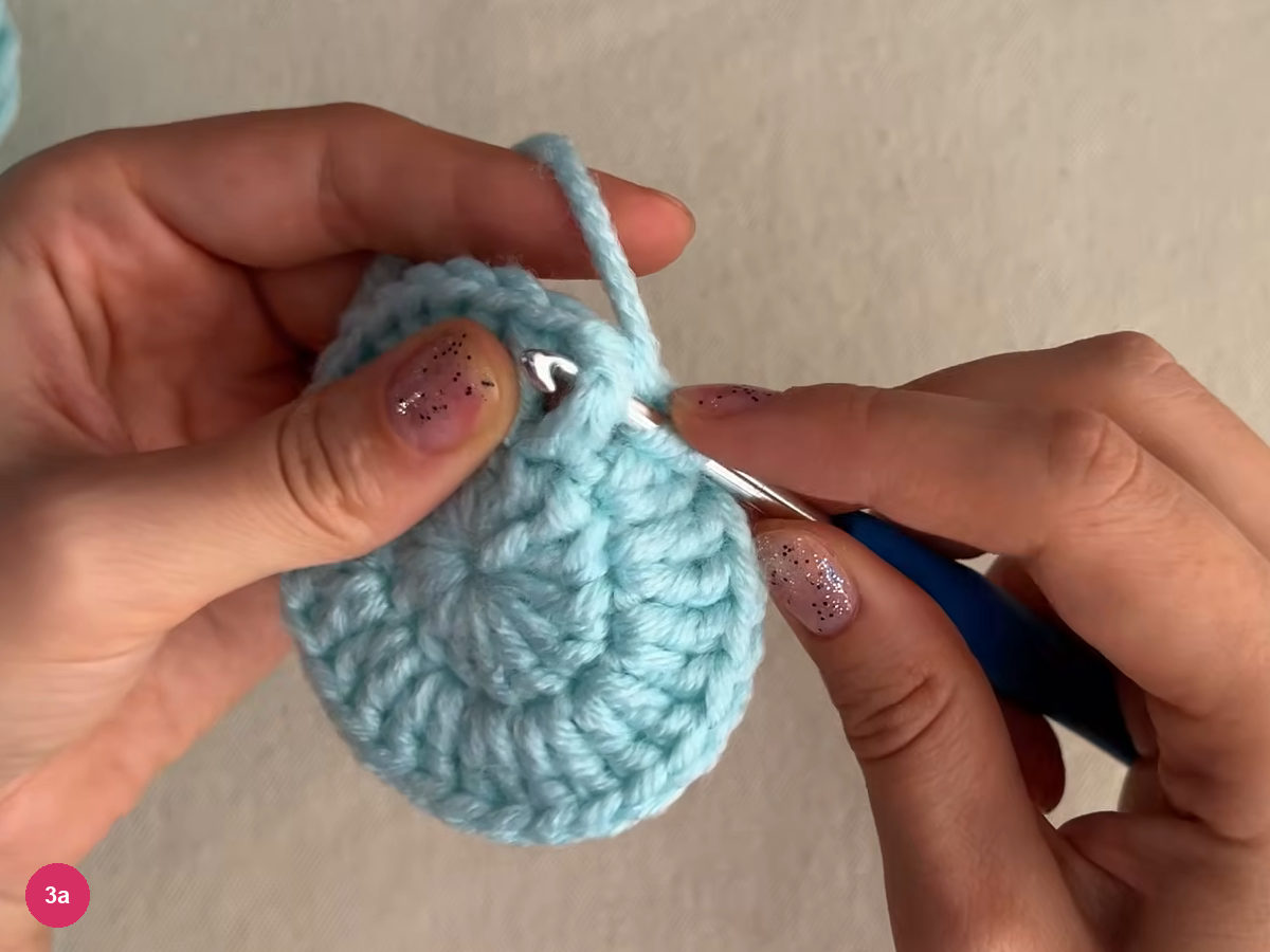 Hook inserted into the edge stitches of the flat mint round with yarn over, as the first raised stitch is worked