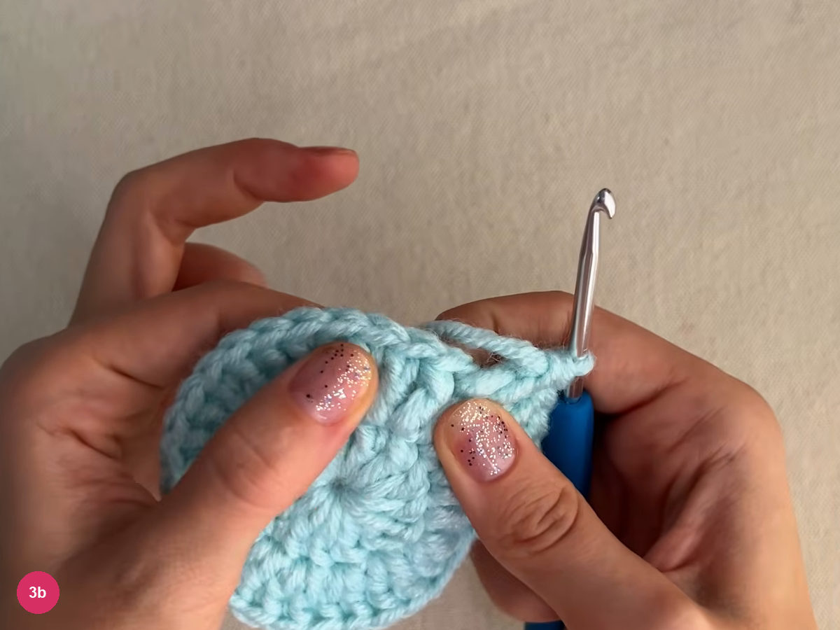 A ridge of raised stitches along the upper right edge of the mint round, with the hook standing at the right