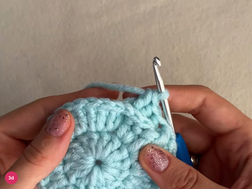 Mint round with a small ridge of raised stitches at its upper right and the hook standing above it