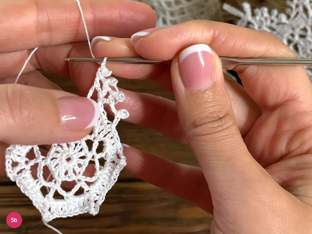 Three double crochet posts with small picot loops rise from one corner space